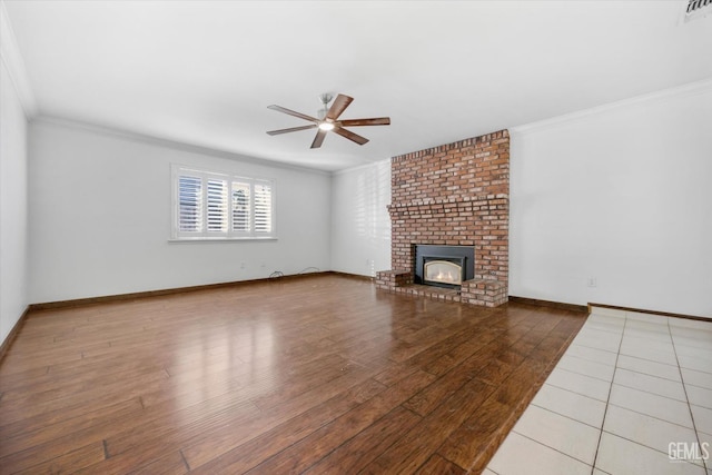 unfurnished living room featuring ceiling fan, crown molding, wood-type flooring, and a fireplace