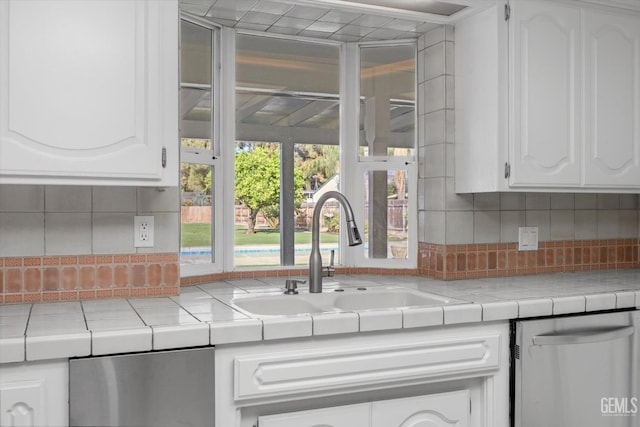 kitchen featuring backsplash, tile countertops, white cabinetry, and sink