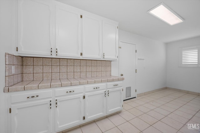 kitchen with tile countertops, white cabinetry, and backsplash