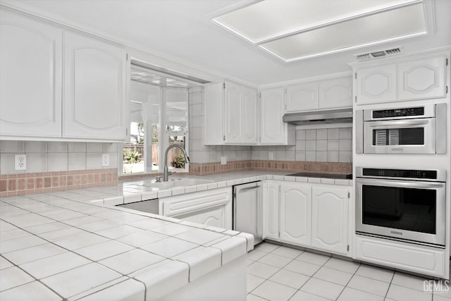 kitchen featuring white cabinetry, tile counters, light tile patterned flooring, and sink