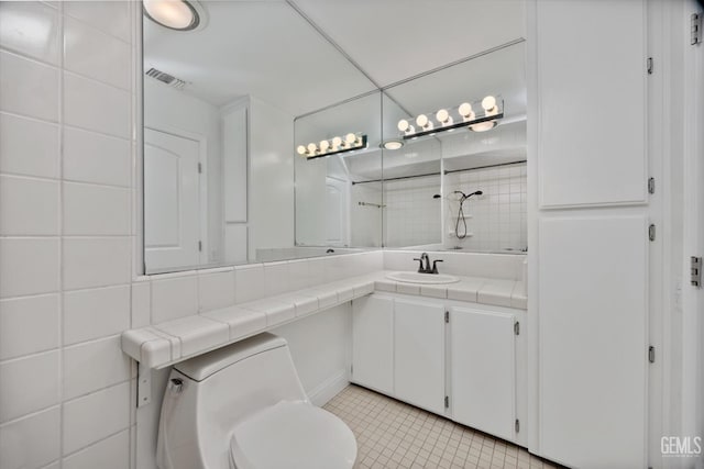 bathroom with tile patterned flooring, vanity, toilet, and tile walls