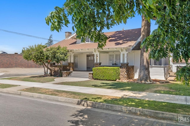 2310 B St, Bakersfield, CA 93301 - view of front facade with a chimney, a porch, a shingled roof, and stone siding