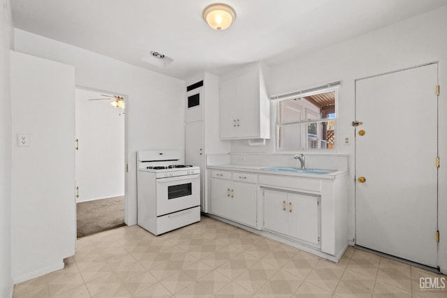 2310 B St, Bakersfield, CA 93301 - kitchen with gas range gas stove, light flooring, light countertops, white cabinets, and ceiling fan