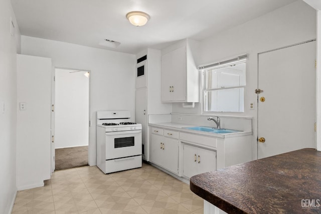 2310 B St, Bakersfield, CA 93301 - kitchen featuring gas range gas stove, light flooring, and white cabinets