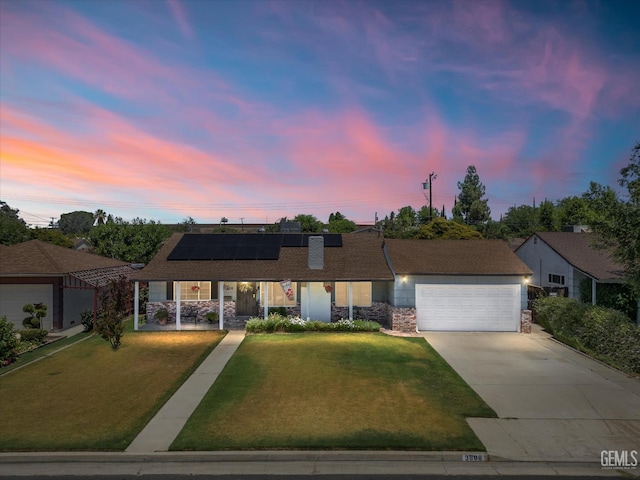 3808 Navajo Ave, Bakersfield, CA 93309 - single story home with stone siding, a garage, concrete driveway, roof mounted solar panels, and a yard