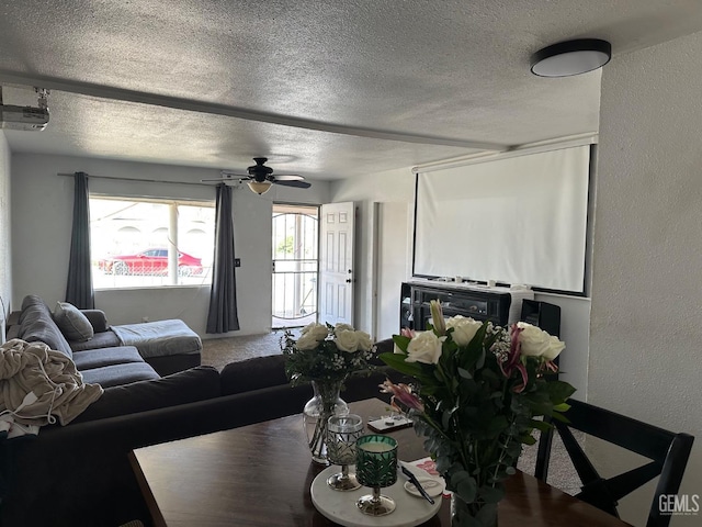 carpeted living area featuring a textured ceiling, a textured wall, and a ceiling fan