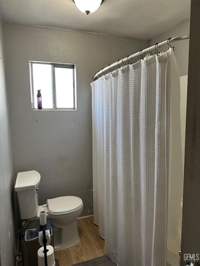 full bathroom featuring toilet, a shower with curtain, a textured ceiling, and wood finished floors