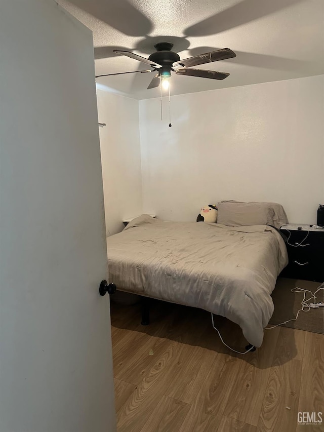 bedroom featuring ceiling fan, a textured ceiling, and wood finished floors