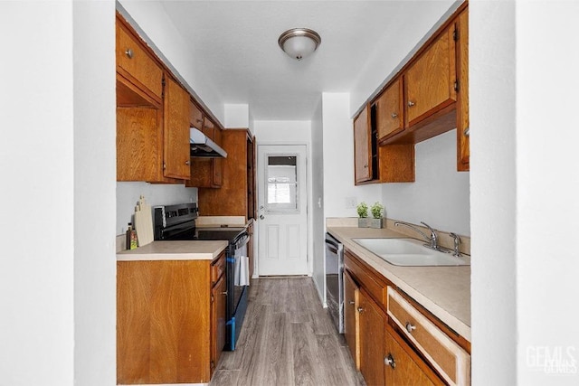 kitchen featuring light countertops, black range with electric stovetop, under cabinet range hood, and a sink