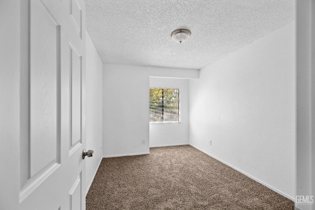 spare room with a textured ceiling, carpet floors, and baseboards