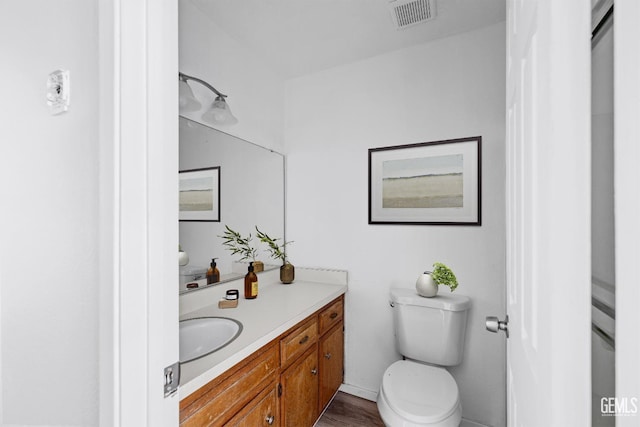 bathroom with toilet, vanity, visible vents, and baseboards