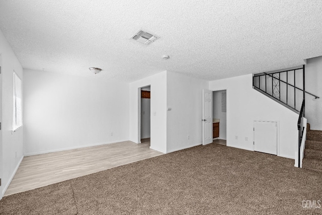 spare room with stairs, carpet floors, a textured ceiling, and visible vents