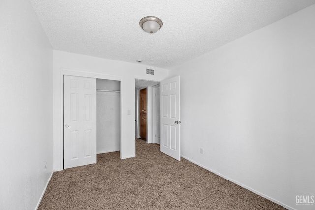 unfurnished bedroom featuring a closet, visible vents, carpet flooring, a textured ceiling, and baseboards