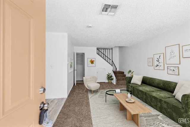 living area featuring stairs, visible vents, and a textured ceiling