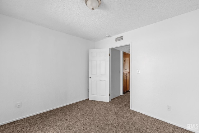 empty room featuring dark colored carpet, visible vents, a textured ceiling, and baseboards