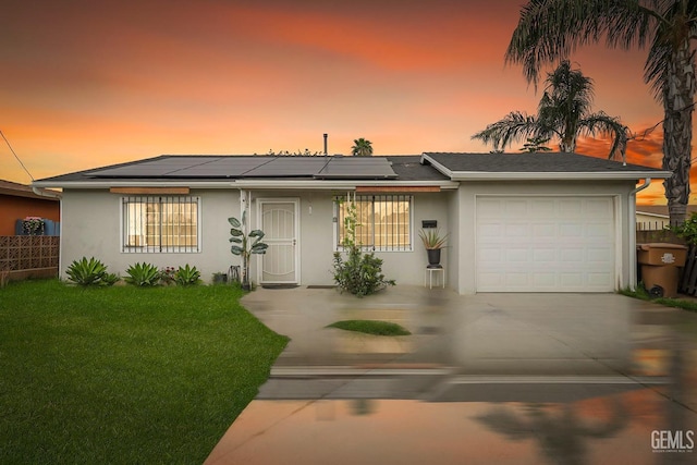 ranch-style house with solar panels, concrete driveway, a garage, a front yard, and stucco siding