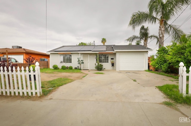 ranch-style house with driveway, roof mounted solar panels, fence, a garage, and stucco siding