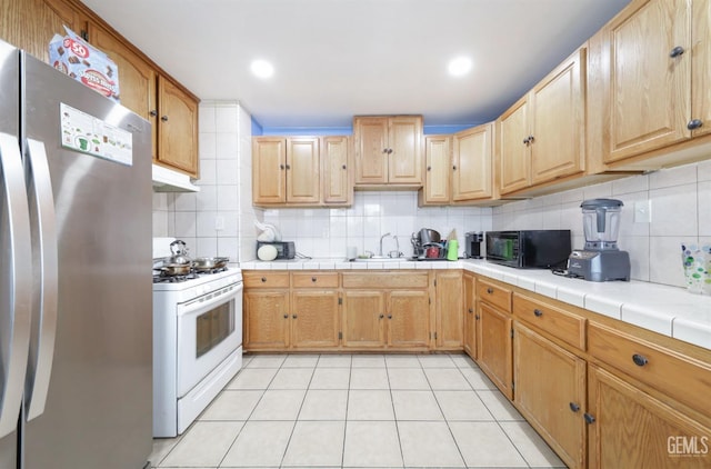 kitchen featuring black microwave, freestanding refrigerator, gas range gas stove, and tasteful backsplash