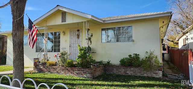 view of front facade featuring a front yard, fence, and stucco siding