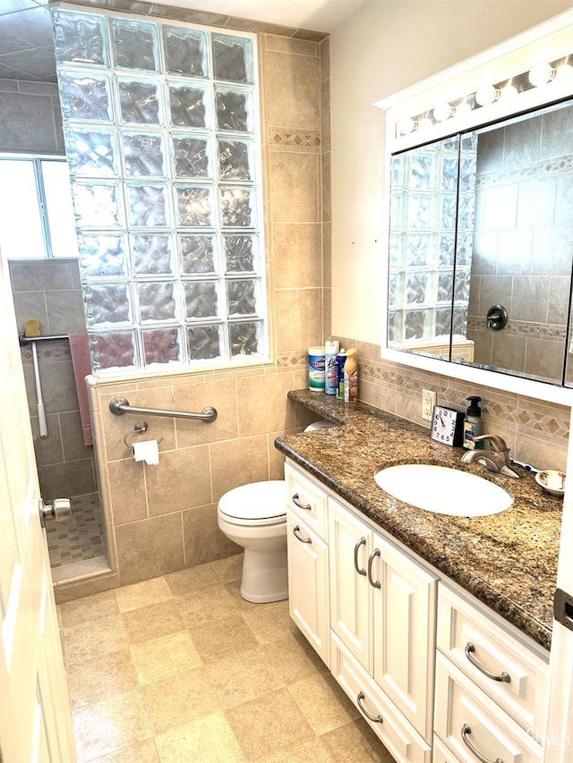 full bathroom with toilet, walk in shower, tile walls, and vanity