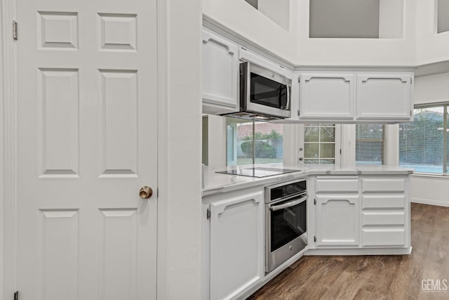 kitchen featuring appliances with stainless steel finishes, wood finished floors, a peninsula, light countertops, and white cabinetry