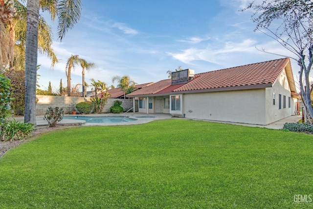 back of house with a fenced in pool, a yard, stucco siding, a fenced backyard, and a tiled roof