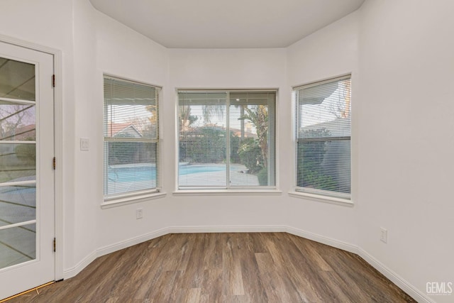 spare room featuring dark wood-type flooring and baseboards