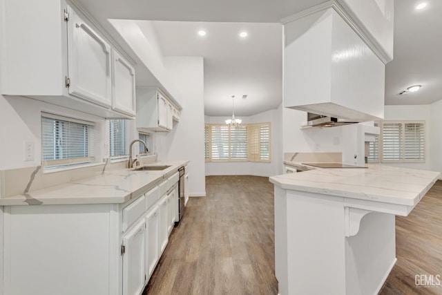 kitchen with a breakfast bar area, a peninsula, white cabinetry, black appliances, and light wood finished floors