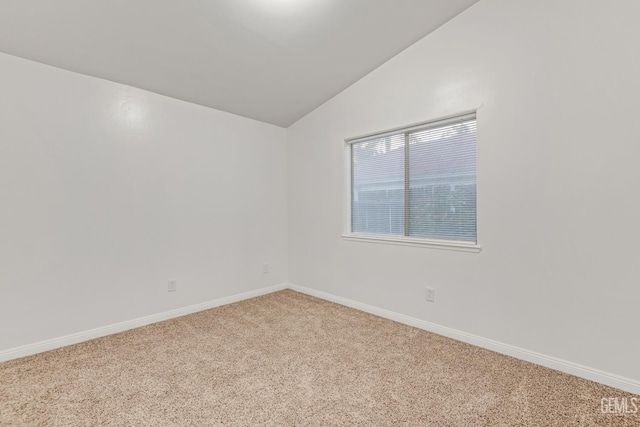 spare room featuring lofted ceiling, carpet, and baseboards