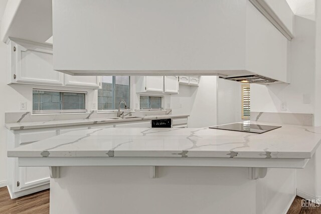 kitchen featuring black appliances, a peninsula, white cabinetry, and a kitchen breakfast bar