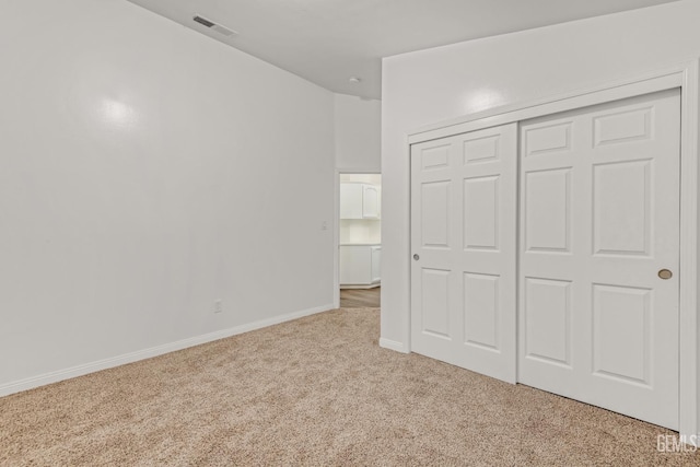 unfurnished bedroom featuring baseboards, a closet, visible vents, and light colored carpet