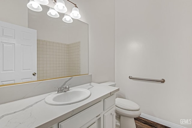 bathroom featuring toilet, vanity, wood finished floors, a chandelier, and baseboards