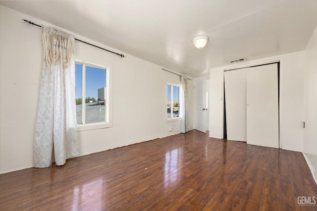 unfurnished bedroom with dark wood-type flooring and a closet