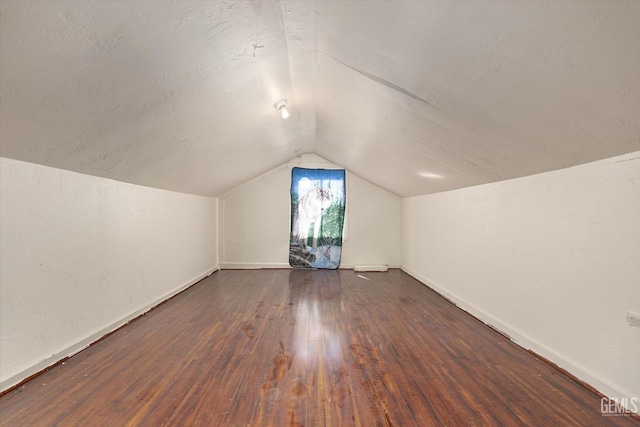 additional living space with lofted ceiling, wood-type flooring, and a textured ceiling