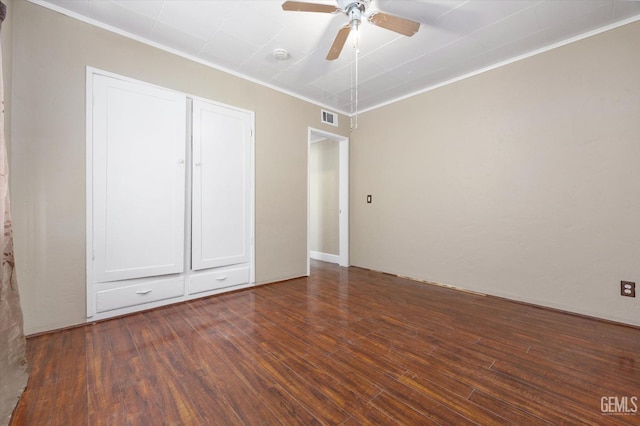 unfurnished bedroom featuring dark hardwood / wood-style flooring, ornamental molding, a closet, and ceiling fan