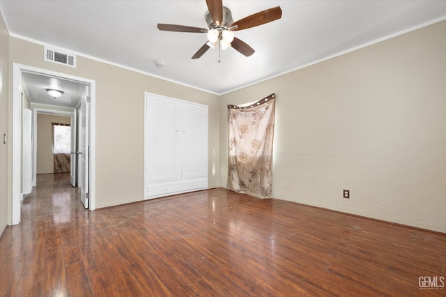 unfurnished bedroom with ornamental molding, ceiling fan, dark hardwood / wood-style flooring, and a closet