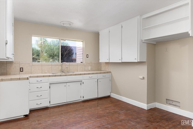 kitchen with sink, tile countertops, white cabinets, and decorative backsplash