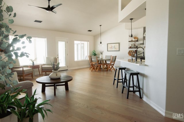 living room featuring wood finished floors, ceiling fan, plenty of natural light, and lofted ceiling