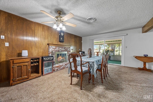 6309 Desert Hills Ave, Bakersfield, CA 93309 - dining area featuring light carpet, wood walls, a ceiling fan, a fireplace, and a textured ceiling