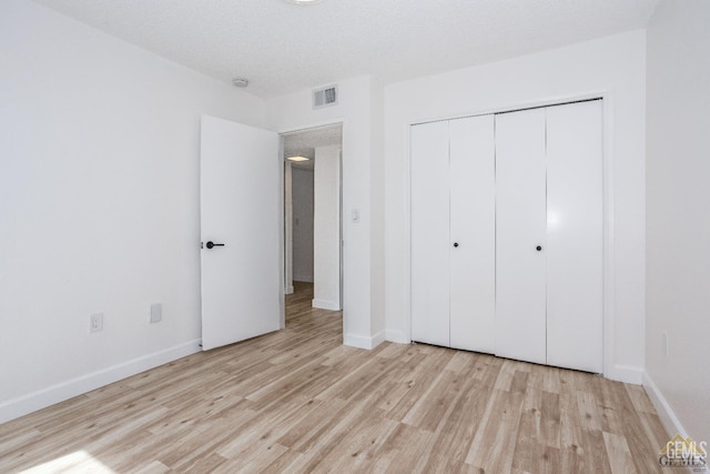 unfurnished bedroom with a textured ceiling, light hardwood / wood-style flooring, and a closet