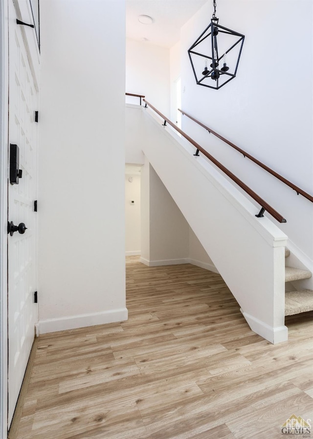 staircase with hardwood / wood-style flooring and an inviting chandelier