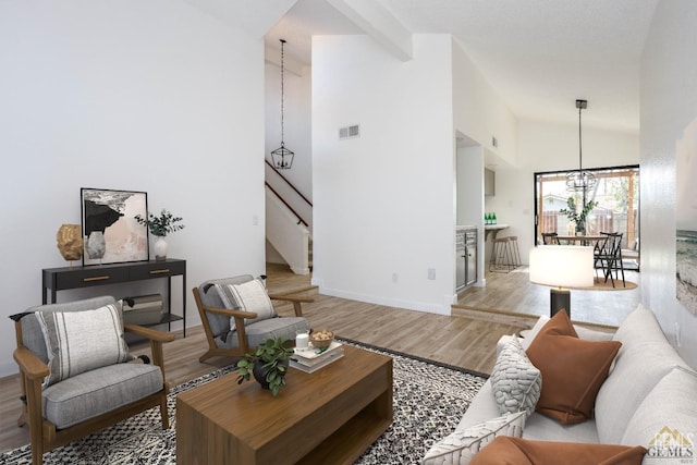 living room with high vaulted ceiling, light hardwood / wood-style floors, and an inviting chandelier