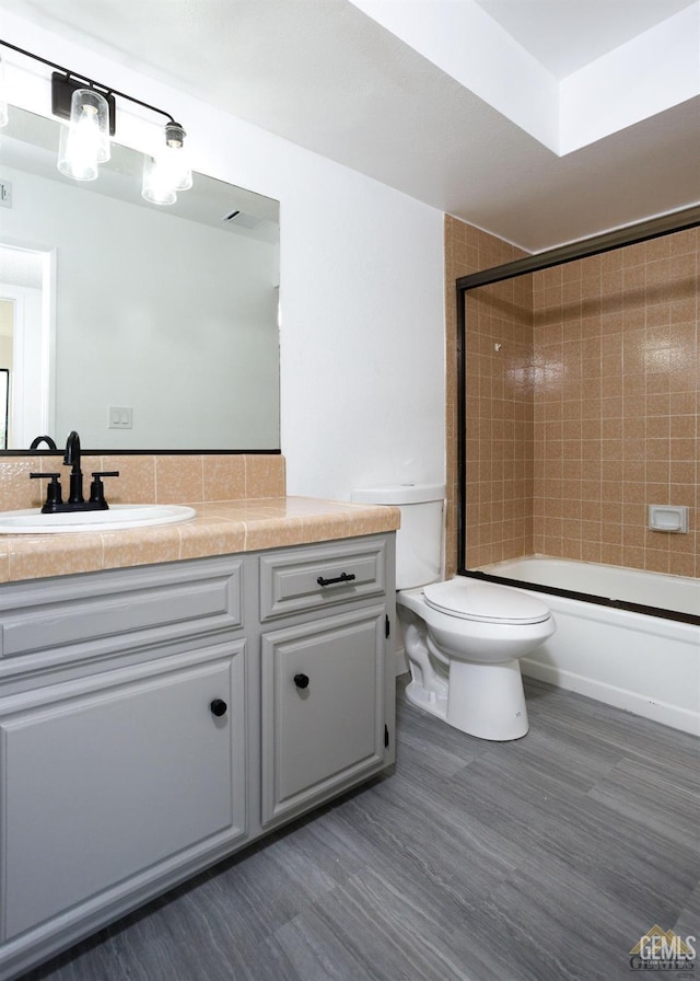 full bathroom with vanity, toilet, wood-type flooring, and tiled shower / bath