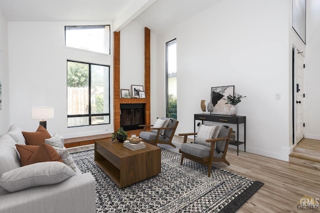 living room with beam ceiling, a fireplace, high vaulted ceiling, and light hardwood / wood-style floors