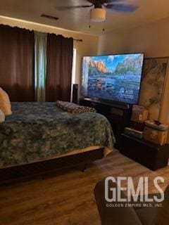 bedroom with wood finished floors, visible vents, and ceiling fan