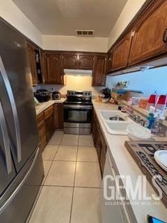 kitchen with visible vents, under cabinet range hood, appliances with stainless steel finishes, light tile patterned flooring, and light countertops