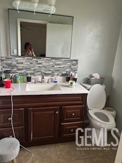 bathroom featuring decorative backsplash, tile patterned floors, toilet, and vanity