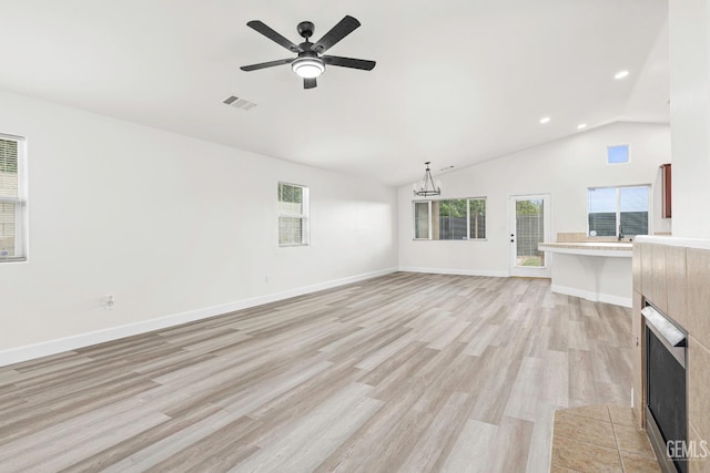 9610 Tahiti Ave, Bakersfield, CA 93311 - unfurnished living room featuring light wood-style floors, a ceiling fan, lofted ceiling, a tile fireplace, and a chandelier