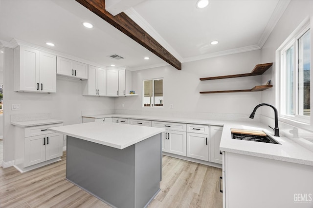 kitchen featuring visible vents, open shelves, beam ceiling, a sink, and light wood-style floors
