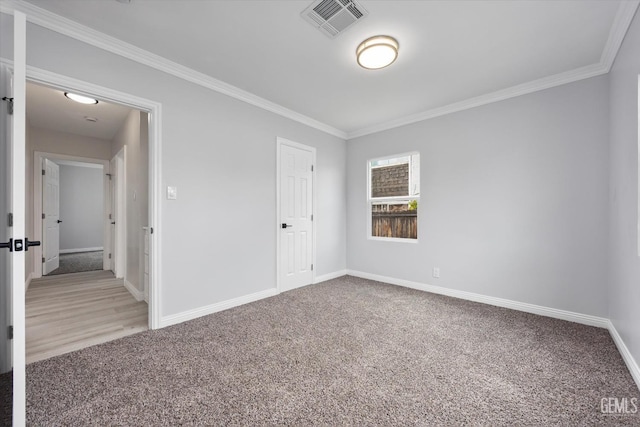 unfurnished bedroom with carpet floors, ornamental molding, baseboards, and visible vents